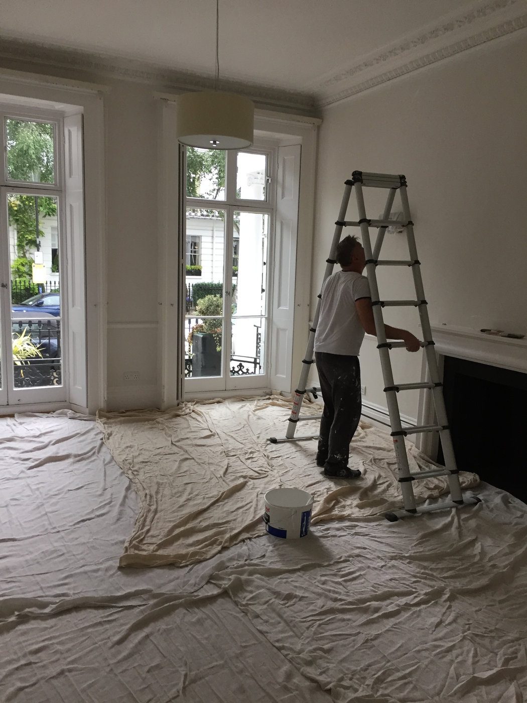 Decorator working from a ladder with floors fully sheeted