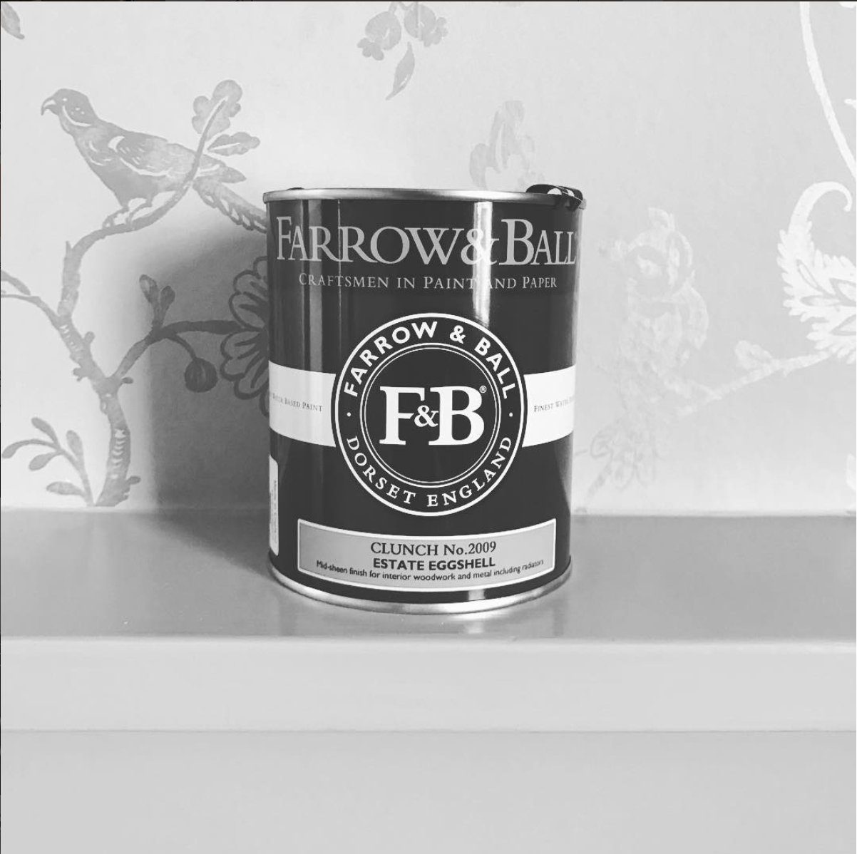 Farrow and Ball paint tin against patterned wallpaper